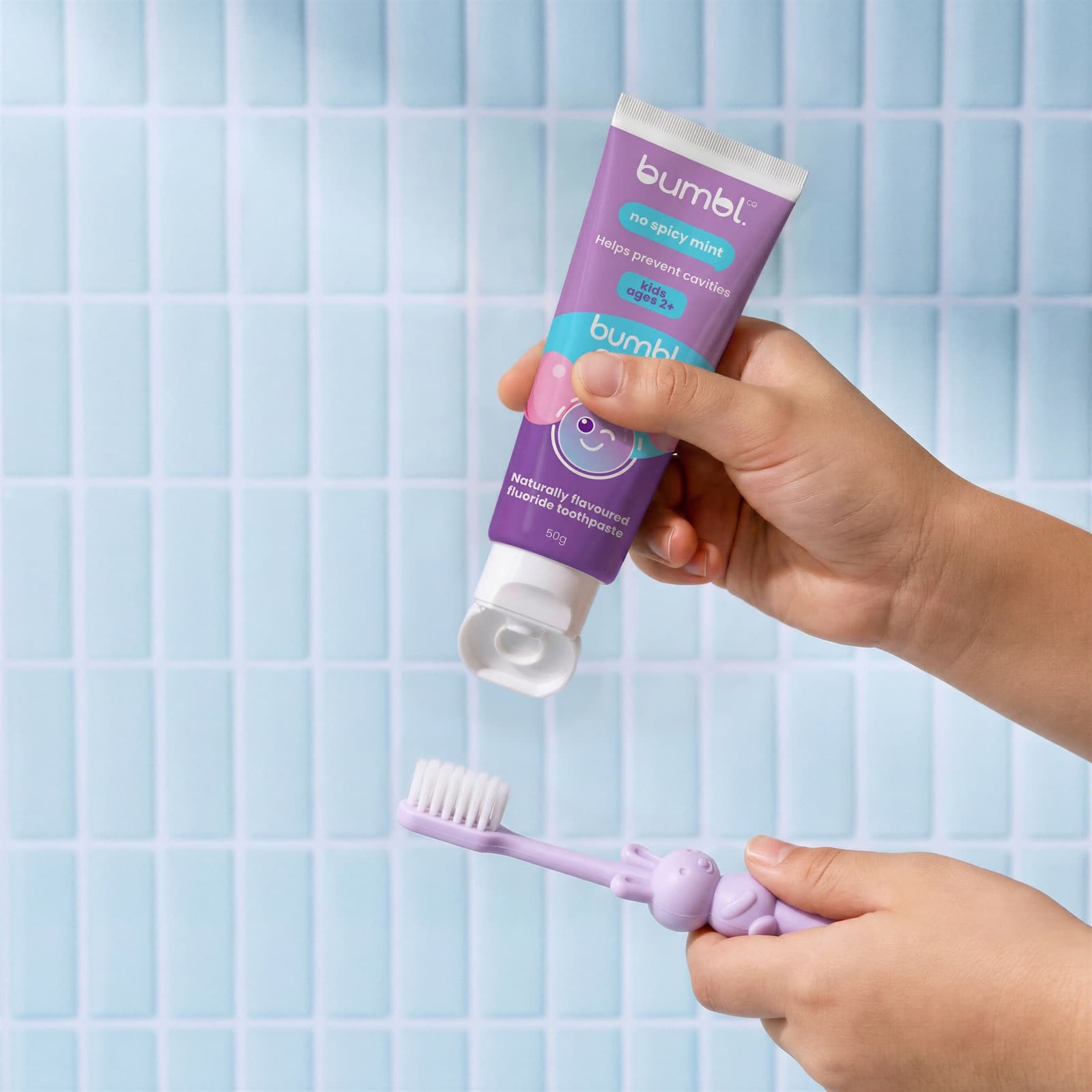 A child squeezing Bumbl Co Bumbl Gum toothpaste onto a toothbrush