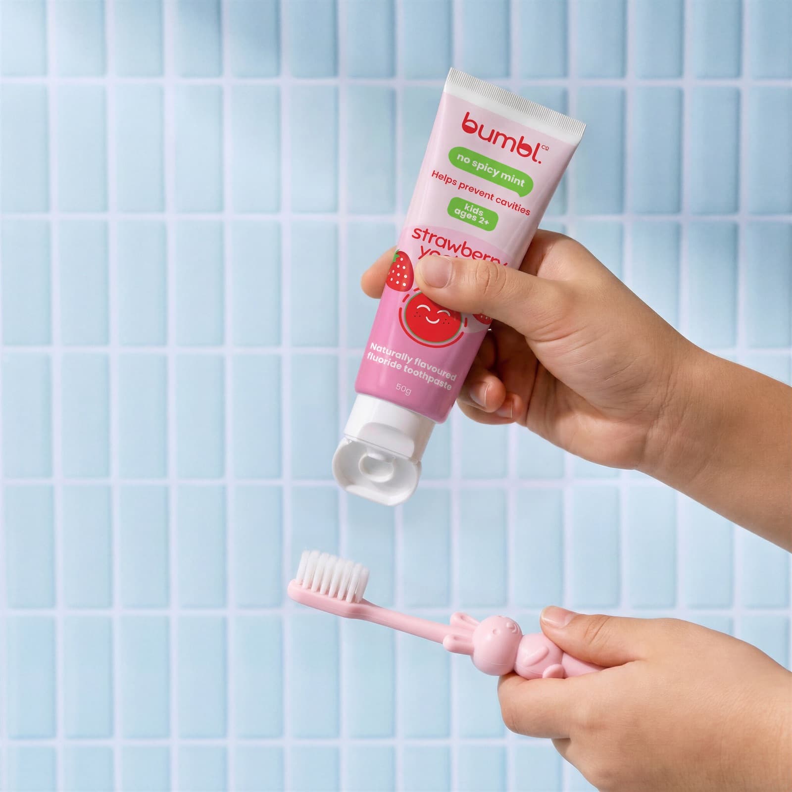 A child squeezing Bumbl Co Strawberry Yoghurt toothpaste onto a toothbrush