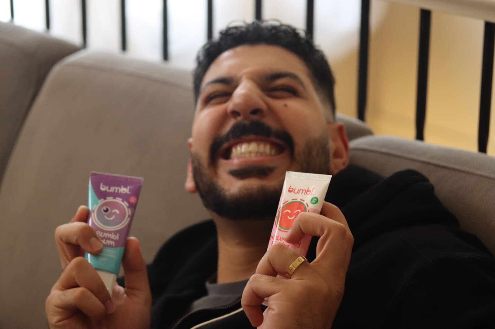 A dad laughing while holding two flavours of Bumbl Co toothpaste
